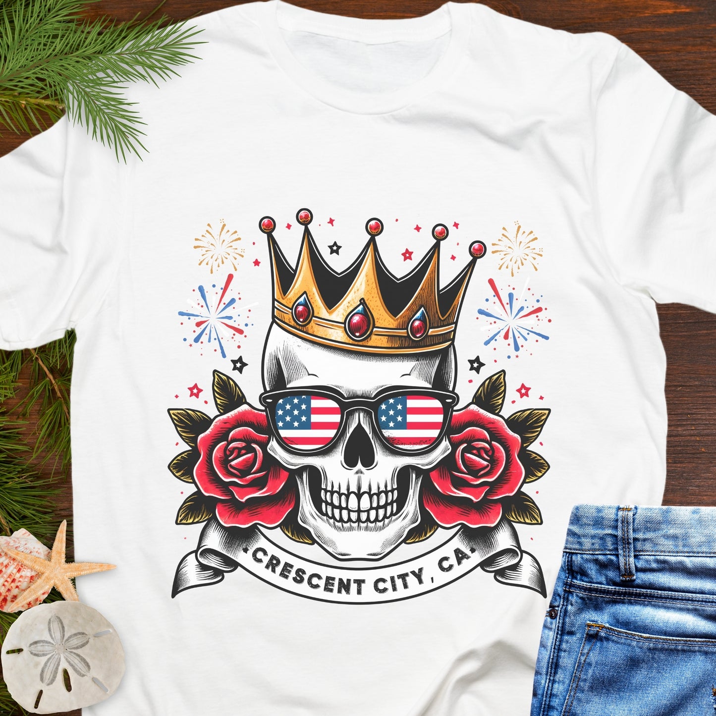White t-shirt with a skull wearing American flag sunglasses, roses, and a crown with a Crescent City, CA banner below.