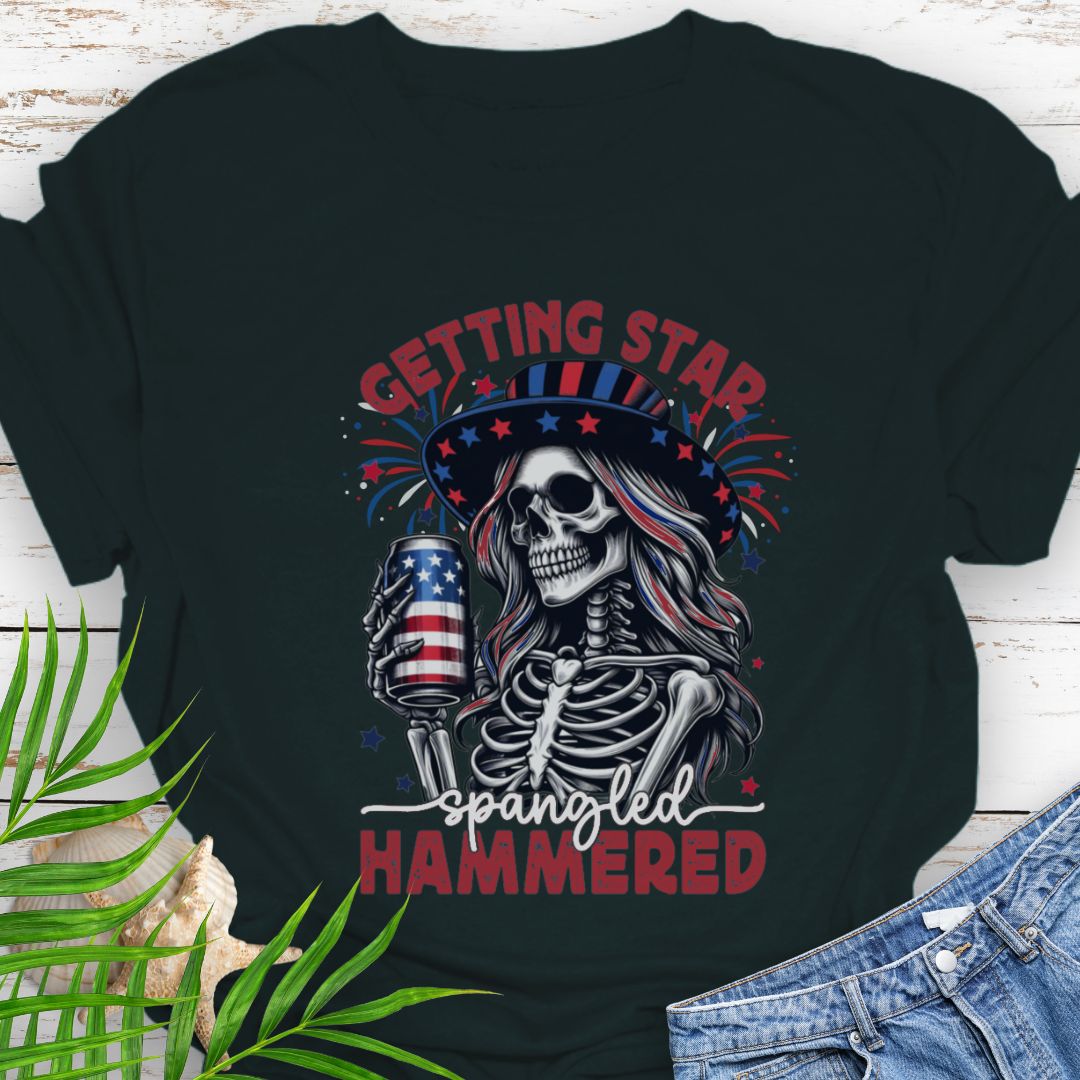 Black T-shirt graphic of a woman skeleton wearing a stars-and-stripes hat, holding an American flag beer can with the phrase “Getting Star Spangled Hammered.