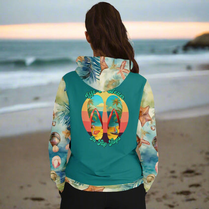 Back view of woman in sweatshirt with teal back with seashell patterned sleeves  and hood Life is better in flip flops with graphic of beach scene flip flops.