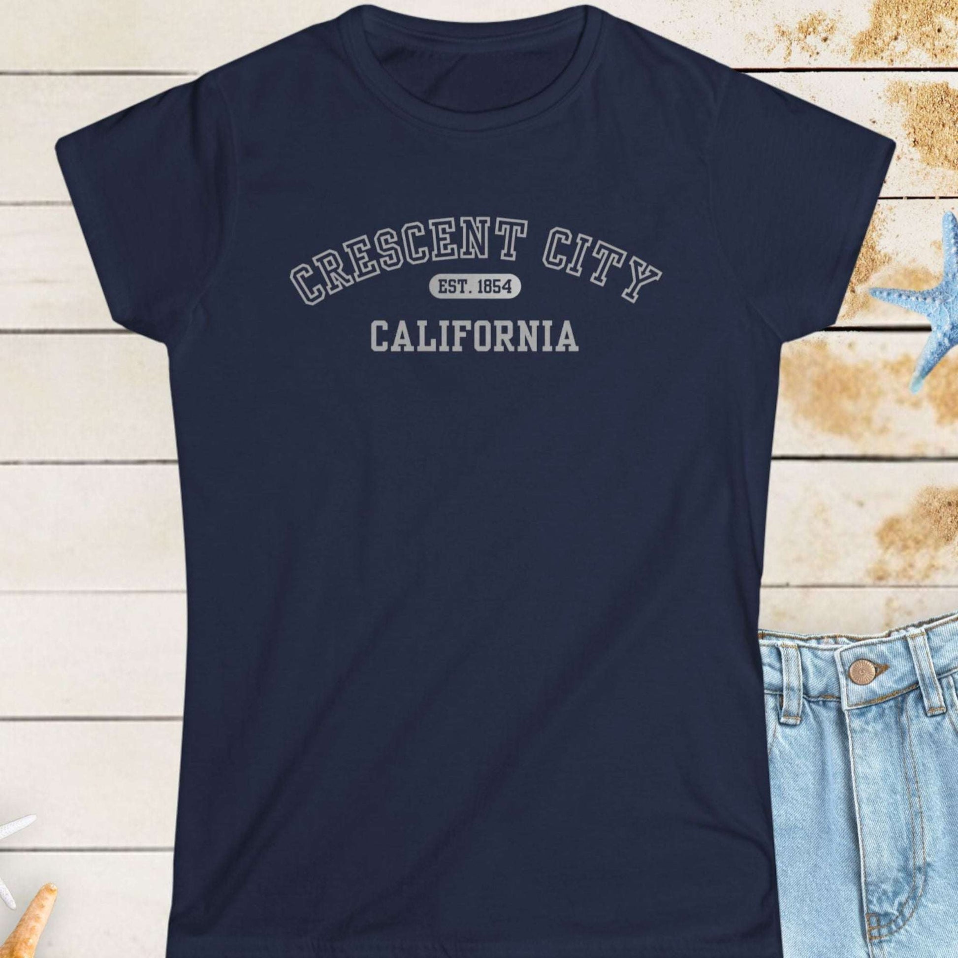 Navy blue t-shirt with 'Crescent City, California' text on a wooden surface with starfish.