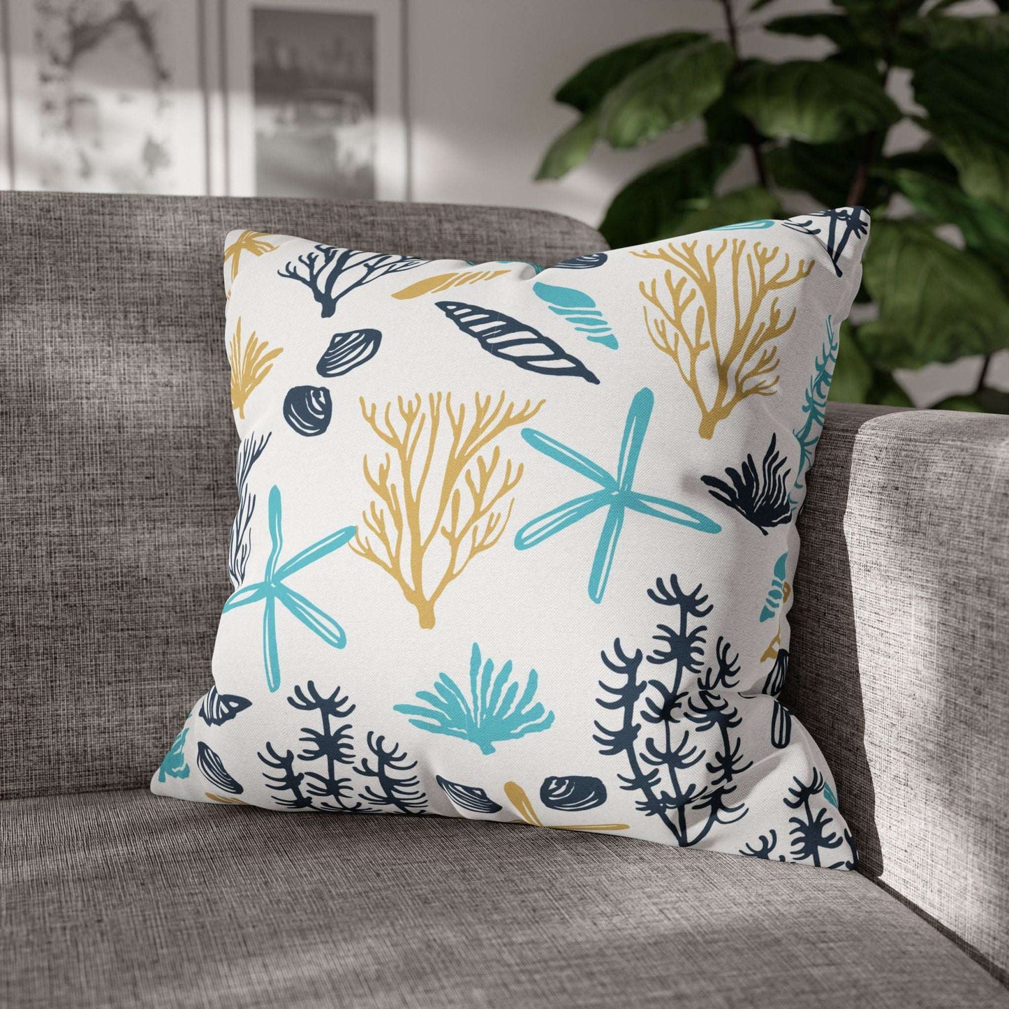 20" x 20" white pillow with coral and starfish pattern on a gray couch.