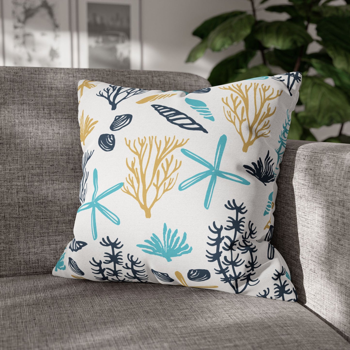 20" x 20" white pillow with coral and starfish pattern on a gray couch.