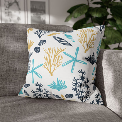 20" x 20" white pillow with coral and starfish pattern on a gray couch.