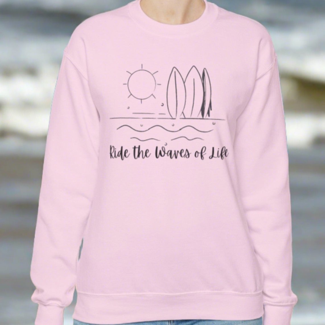 Pink crewneck sweatshirt with waves, surfboards and sun with the words Ride the Waves of Life