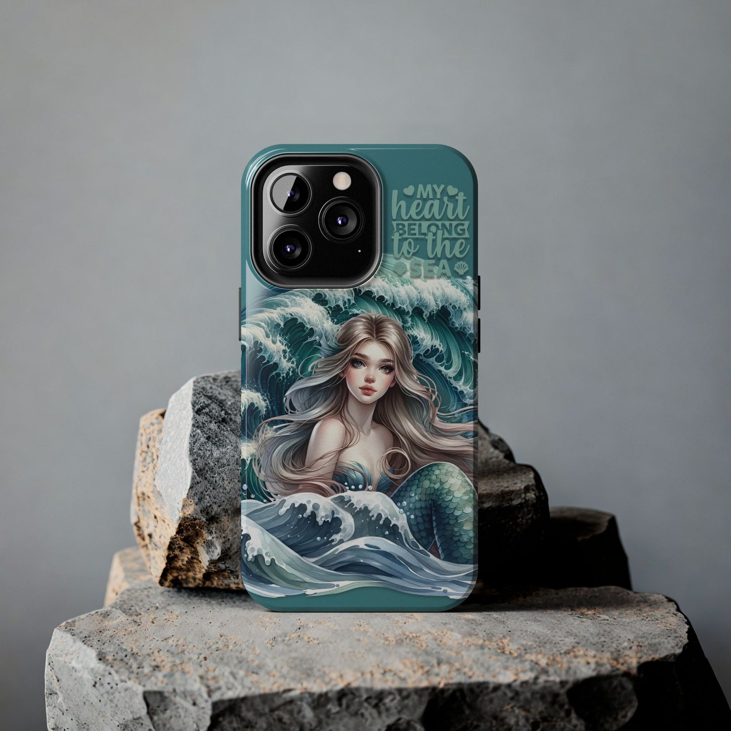 Phone Case with Flowy mermaid with ocean wave behind and text My Heart Belongs to the Sea against rock