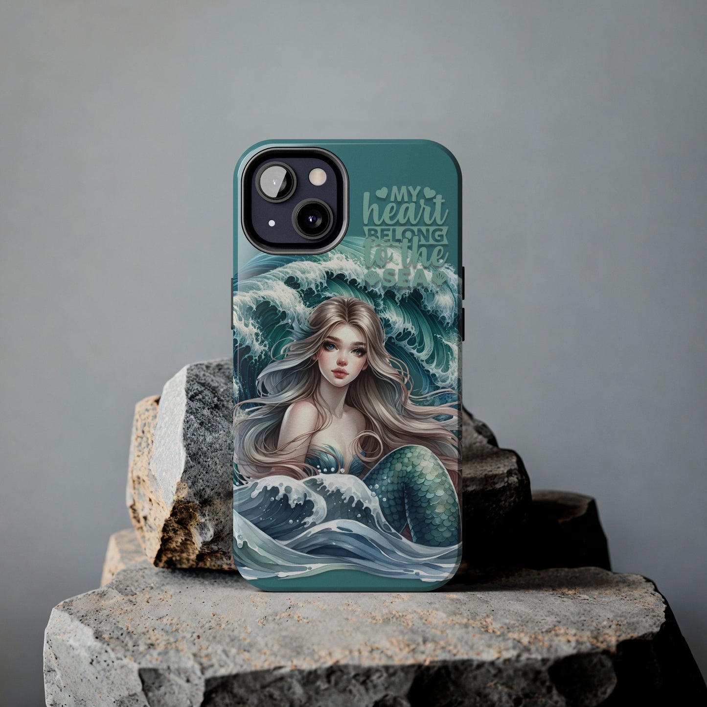 Phone Case with Flowy mermaid with ocean wave behind and text My Heart Belongs to the Sea against rock