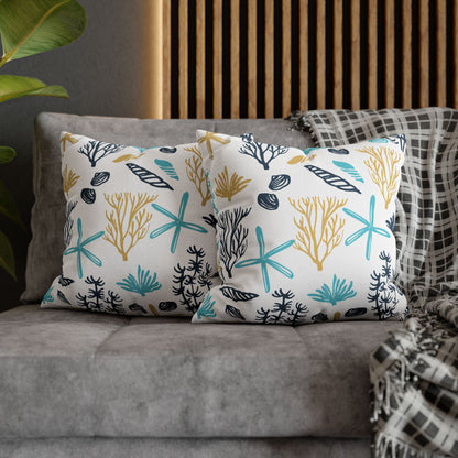 Two 18" x 18" white pillows with coral and starfish pattern on a gray couch.