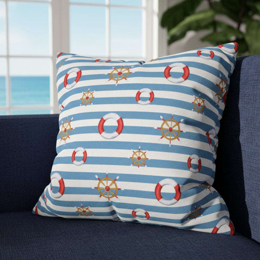 Nautical-themed pillow with stripes and ship wheel patterns on a gray couch.