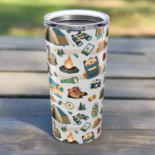 20oz tumbler with light wood background and repeating pattern of hiking boots, tents, campfires, flashlights, maps, and backpacks; glossy finish with secure lid.