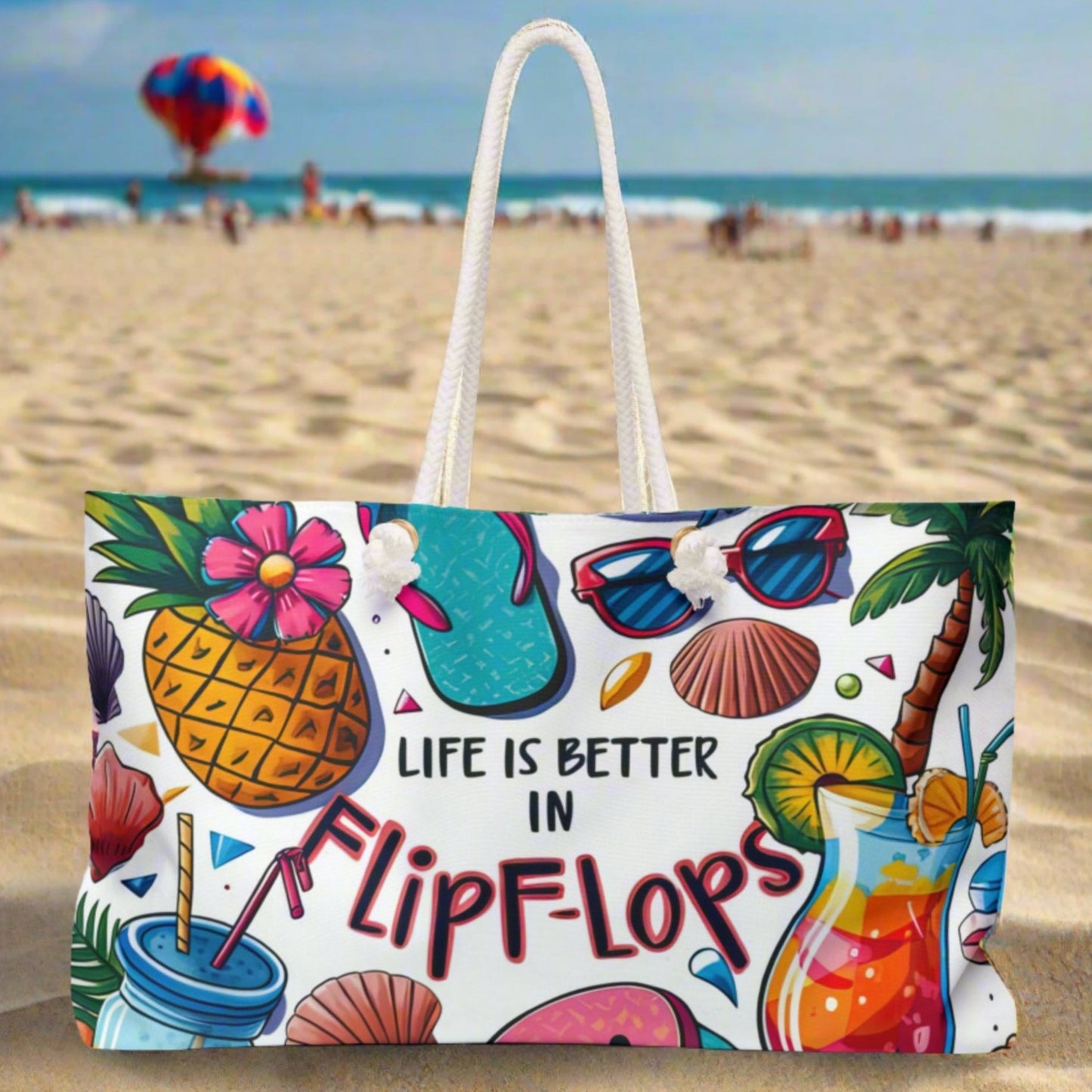 A weekender bag with a white background with pictures of a pineapple, cocktails, seashells and palm tree and says life is better in flip flops