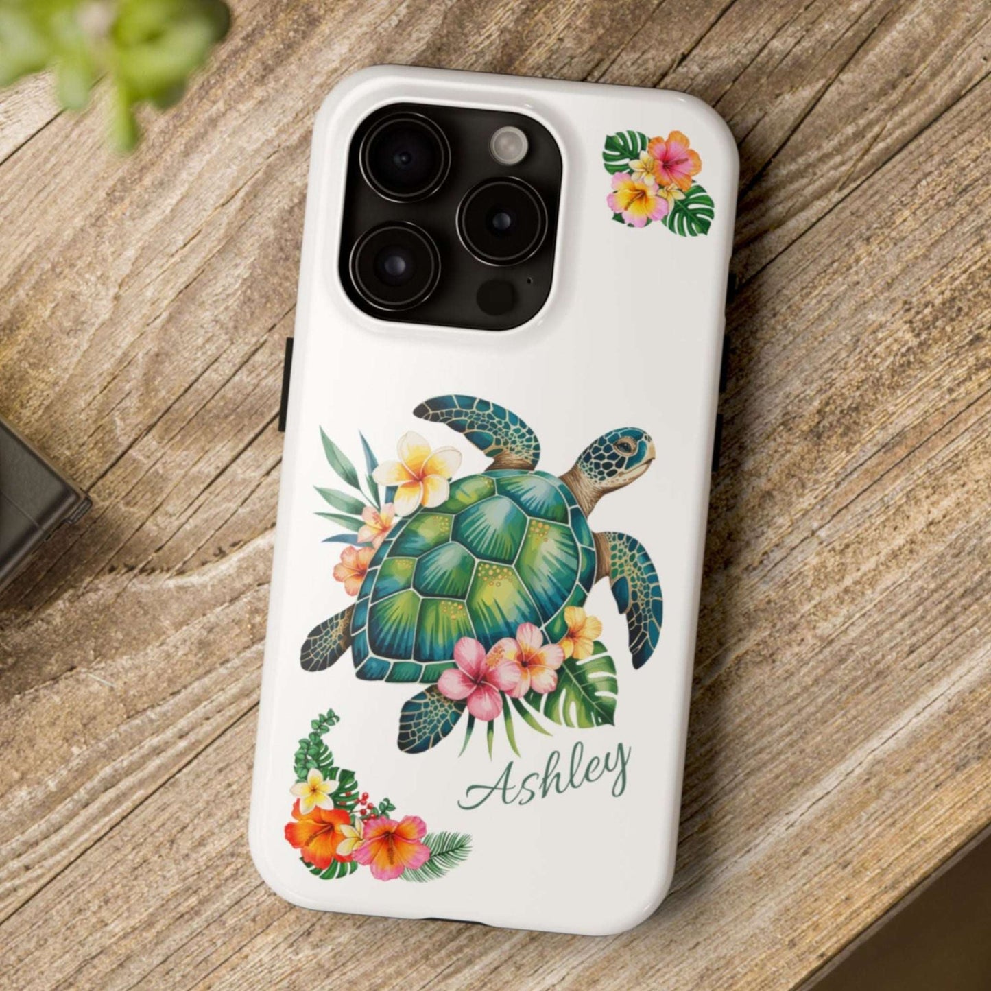 iPhone 15 case with a white background and a sea turtle with hibiscus flowers, with more hibiscus flowers around the sides.