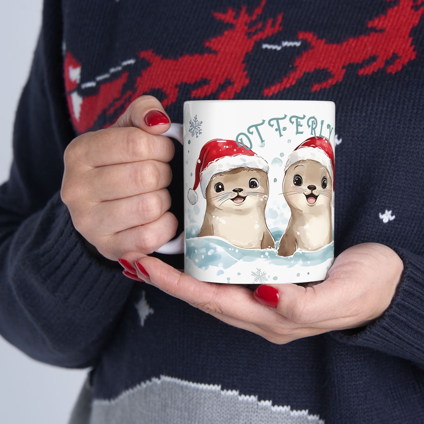 Person holding a mug with otters wearing Santa hats against a festive sweater background