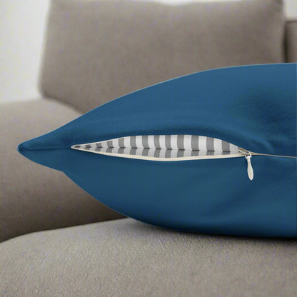 Blue pillow with a zipper on a gray couch.