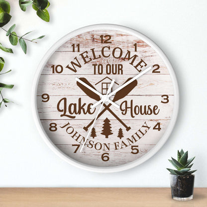 Wall clock with 'Welcome to our Lake House' text and oar design on a wooden background.