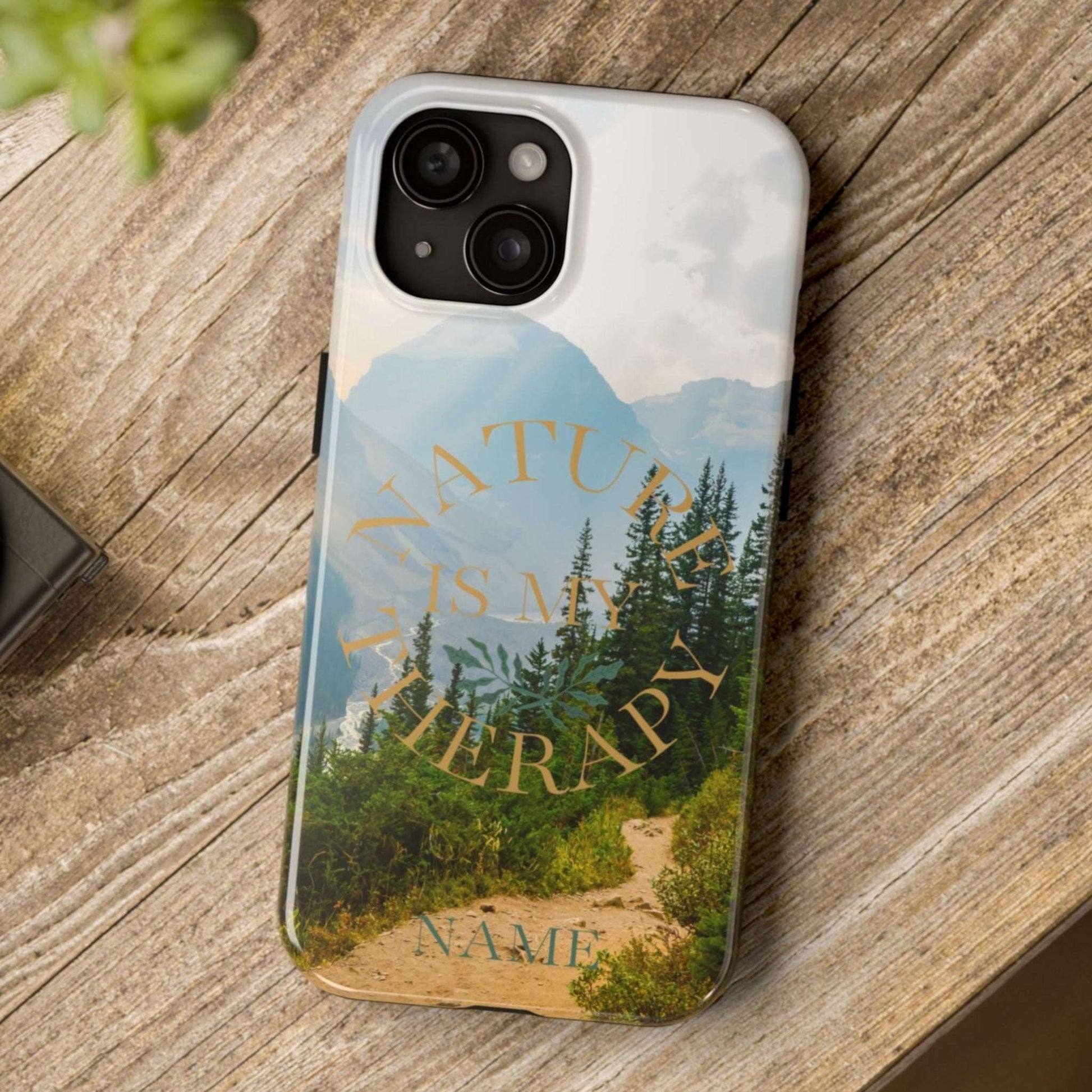 Phone case with nature design and text on a wooden surface