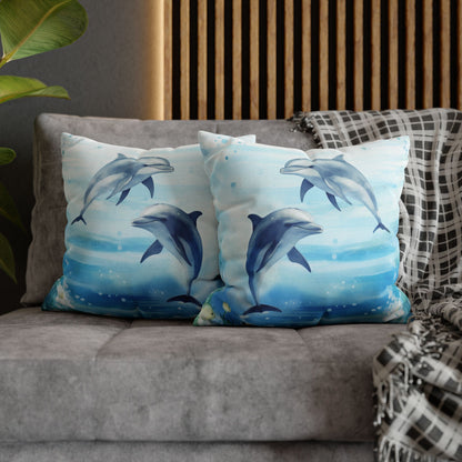 Two decorative pillow cover with a watercolor design of two dolphins in the water with flowers along the bottom edges showing the double-sided print.