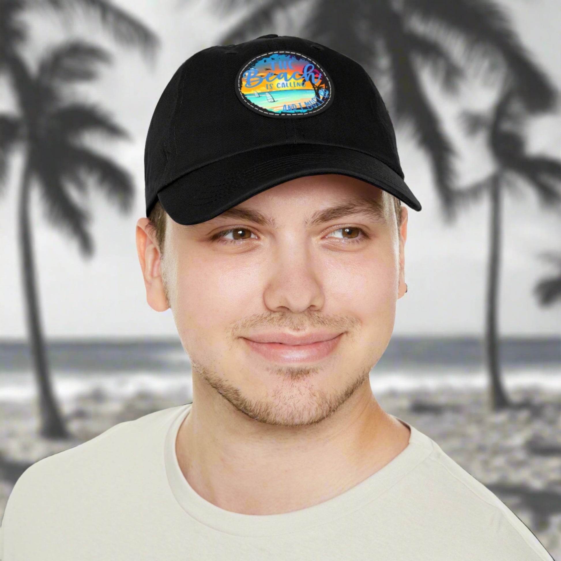 Black hat with a leather patch with picture of beach scene and text The beach is calling and I must go.