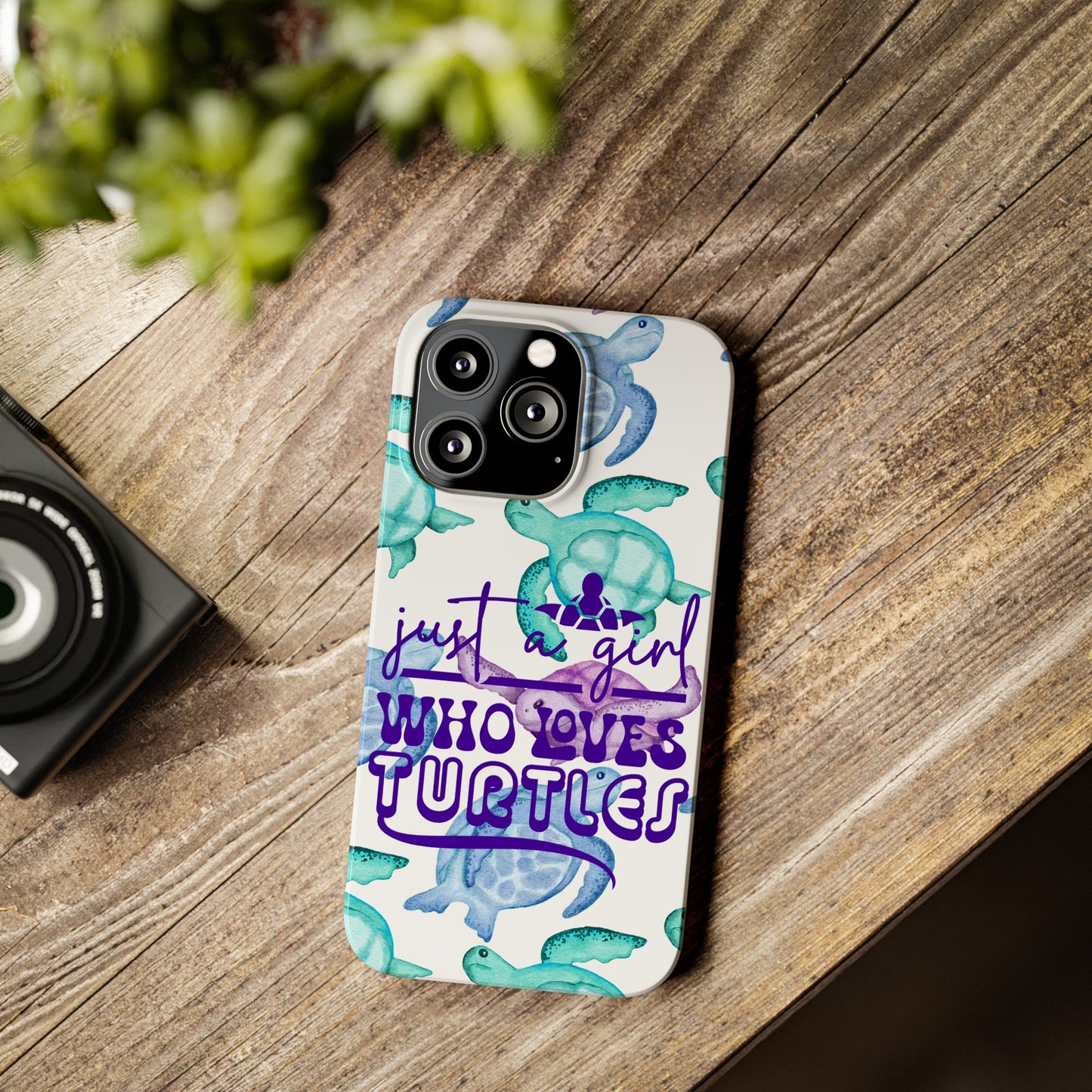 Iphone case with turquoise, blue and purple sea turtles that says  Just a Girl Who Loves Sea turtles laying on wood desk