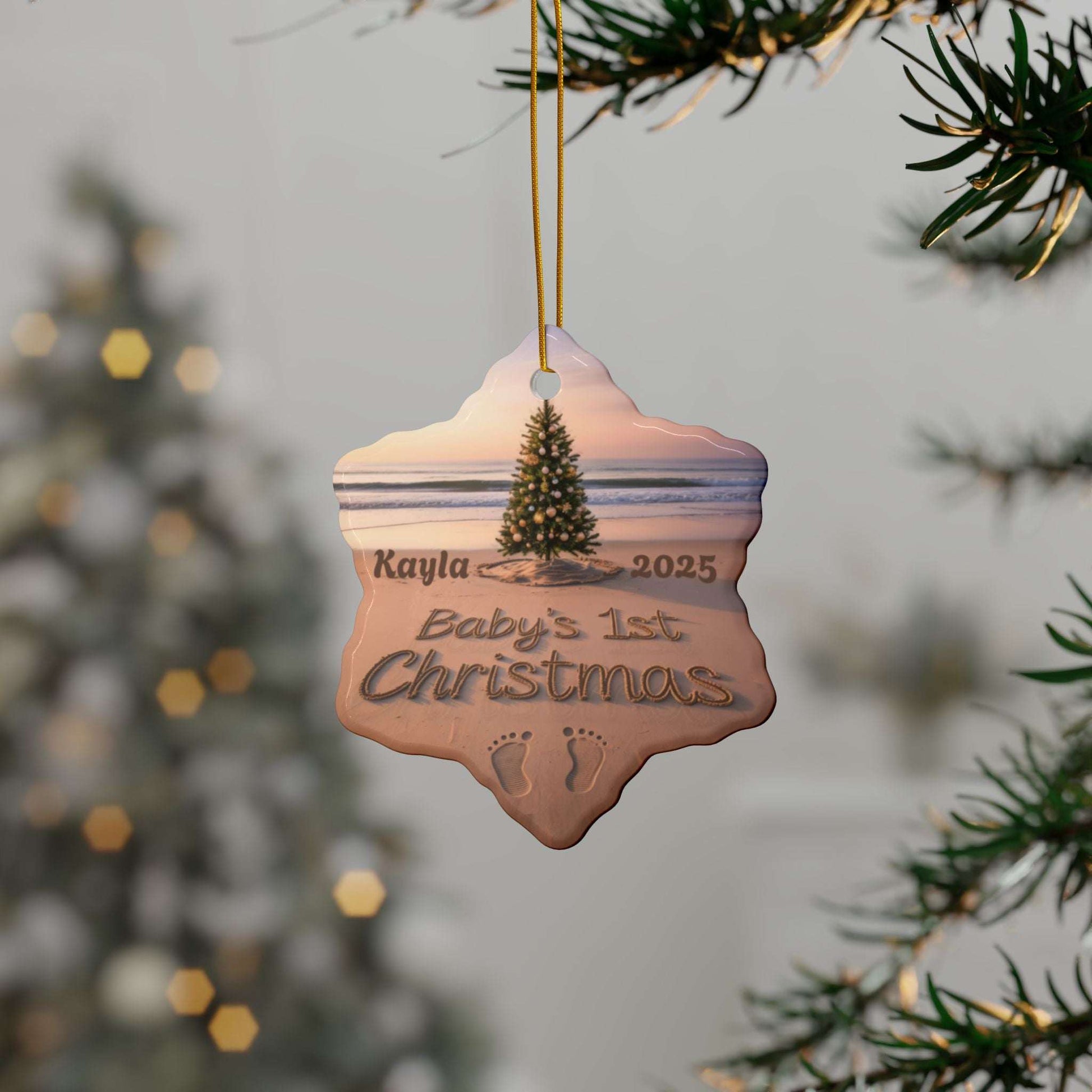 Decorative ornament for 'Kayla's Baby's 1st Christmas' hanging on a tree branch with a blurred festive background.