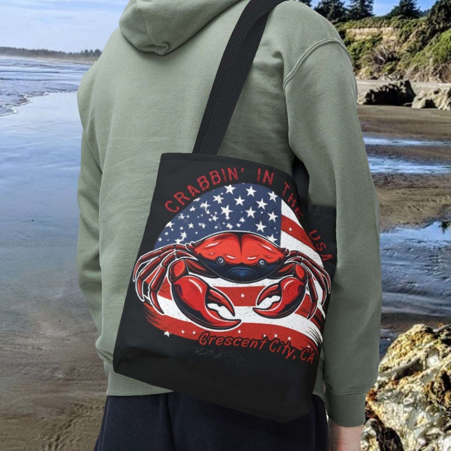 A black tote bag with an American Flag design with a crab coming out and says Crabbin' in the USA and Crescent City, CA.  