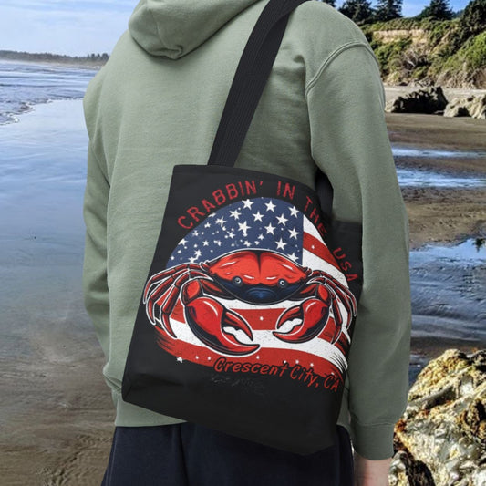 A black tote bag with an American Flag design with a crab coming out and says Crabbin' in the USA and Crescent City, CA.  