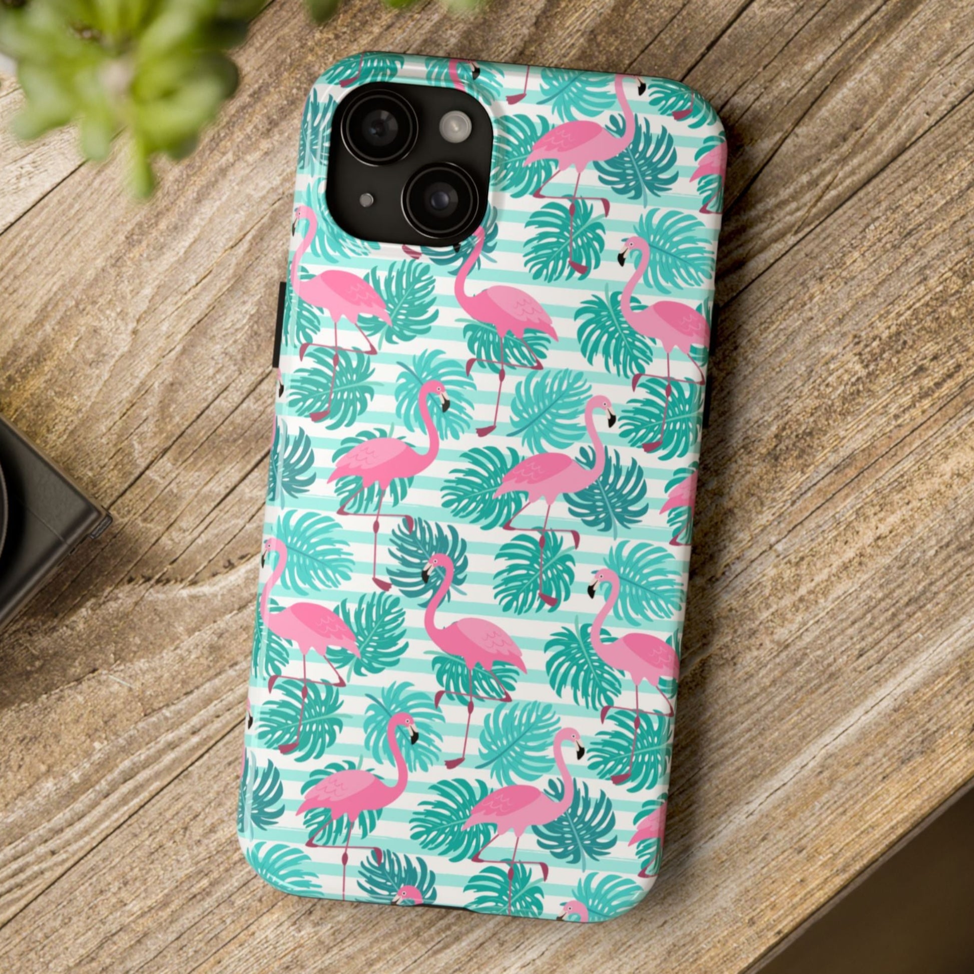 Phone case with flamingo and leaf pattern on a wooden surface