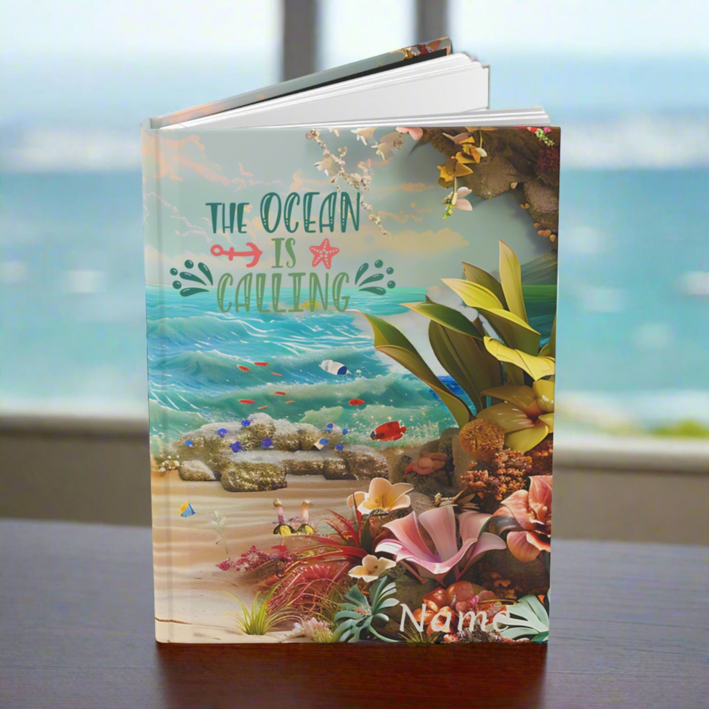 a hardcover journal laying open to show front and back with an ocean scene with flowers and the text the ocean is calling