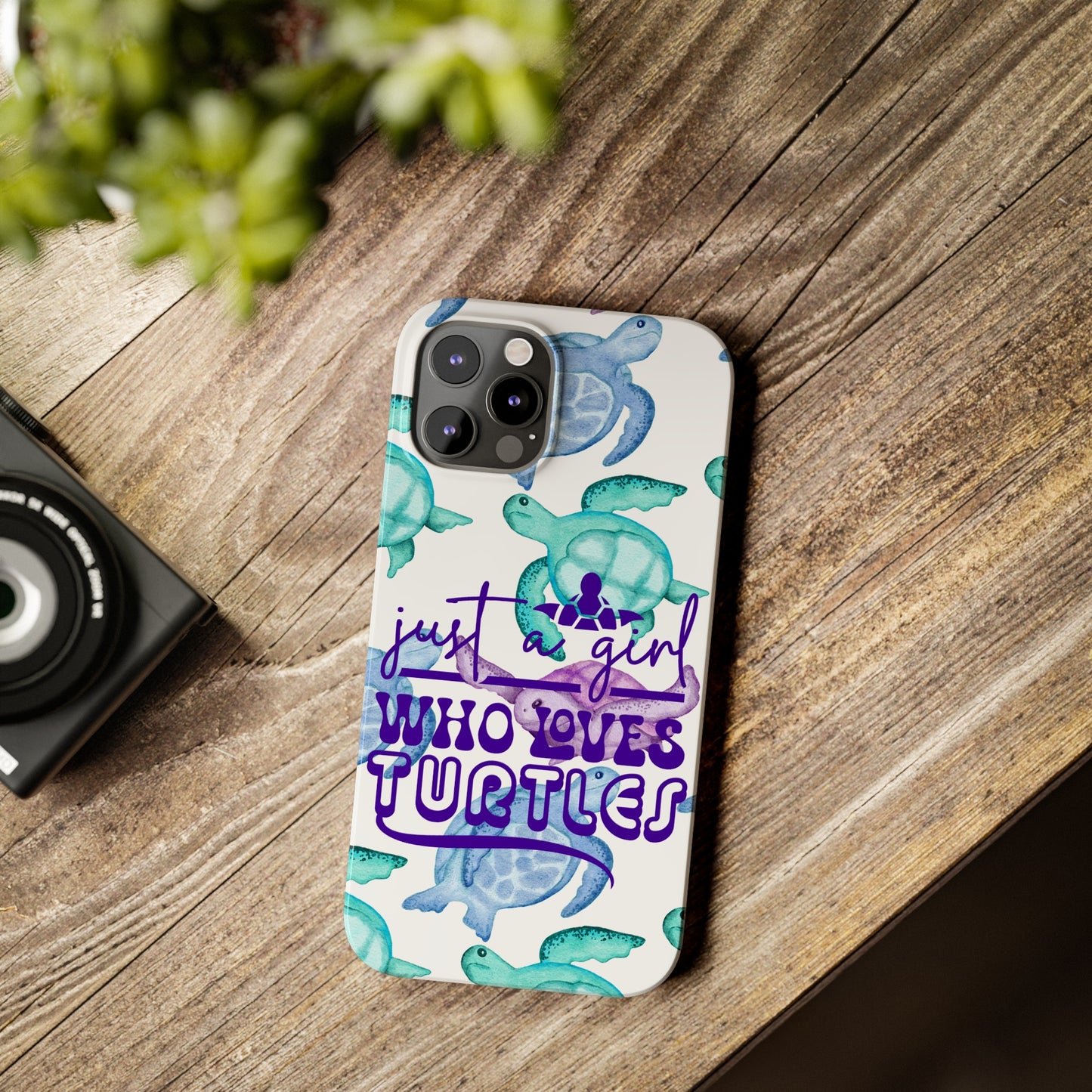 Iphone case with turquoise, blue and purple sea turtles that says  Just a Girl Who Loves Sea turtles laying on wood desk