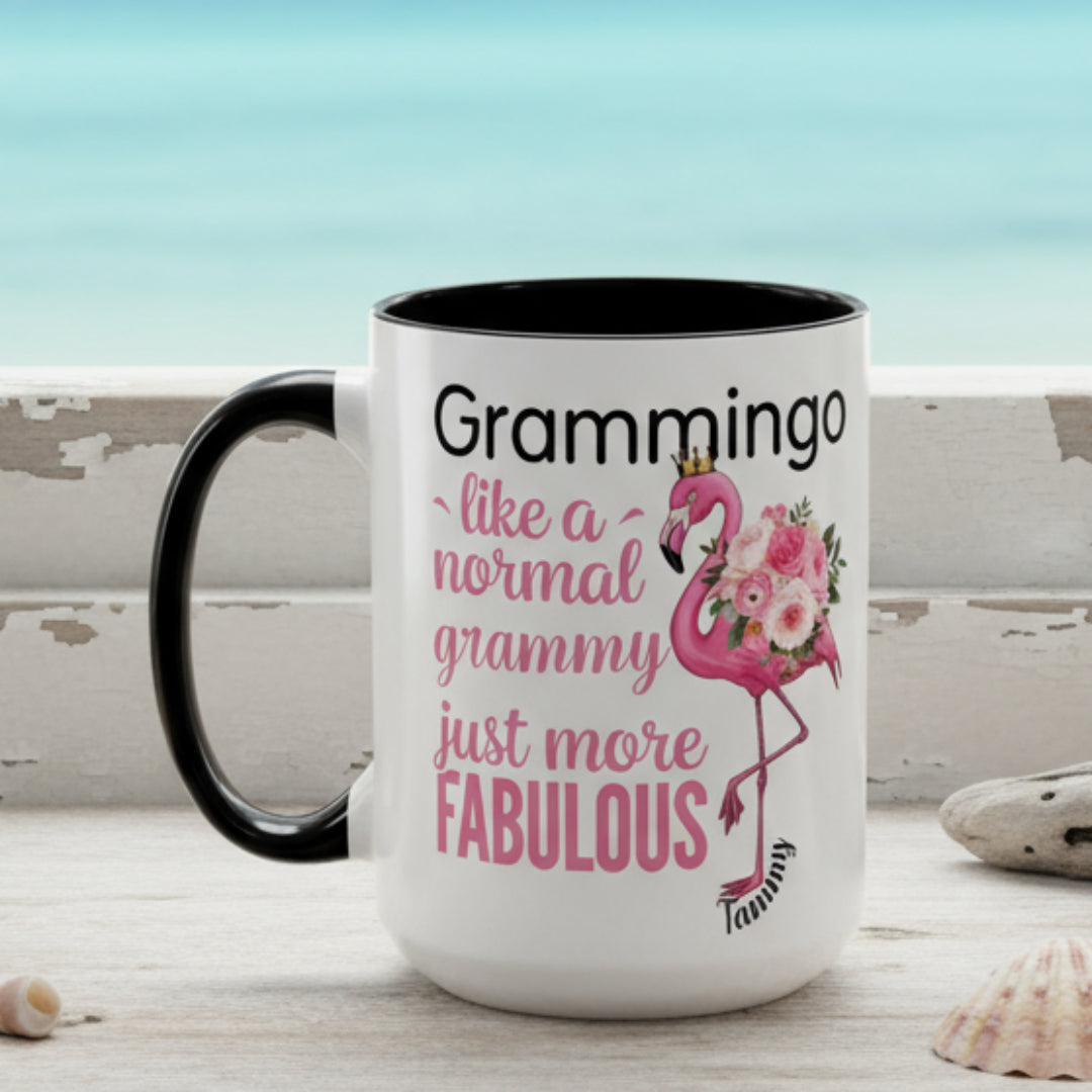 Ceramic coffee mug featuring a flamingo adorned with flowers and the text “Grammingo like a normal Grammy just more fabulous,” available with white, pink, or black handle options.
