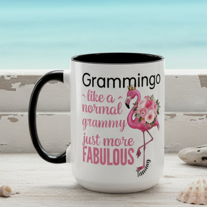 Ceramic coffee mug featuring a flamingo adorned with flowers and the text “Grammingo like a normal Grammy just more fabulous,” available with white, pink, or black handle options.