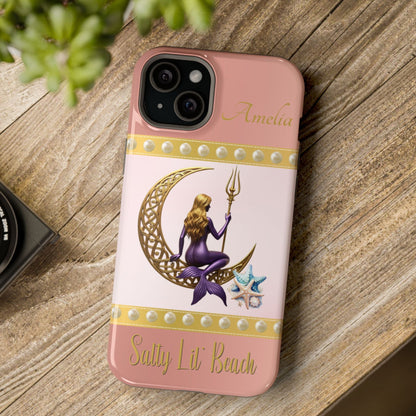 Phone case with a design of a mermaid and crescent moon on a pink background, placed on a wooden surface.