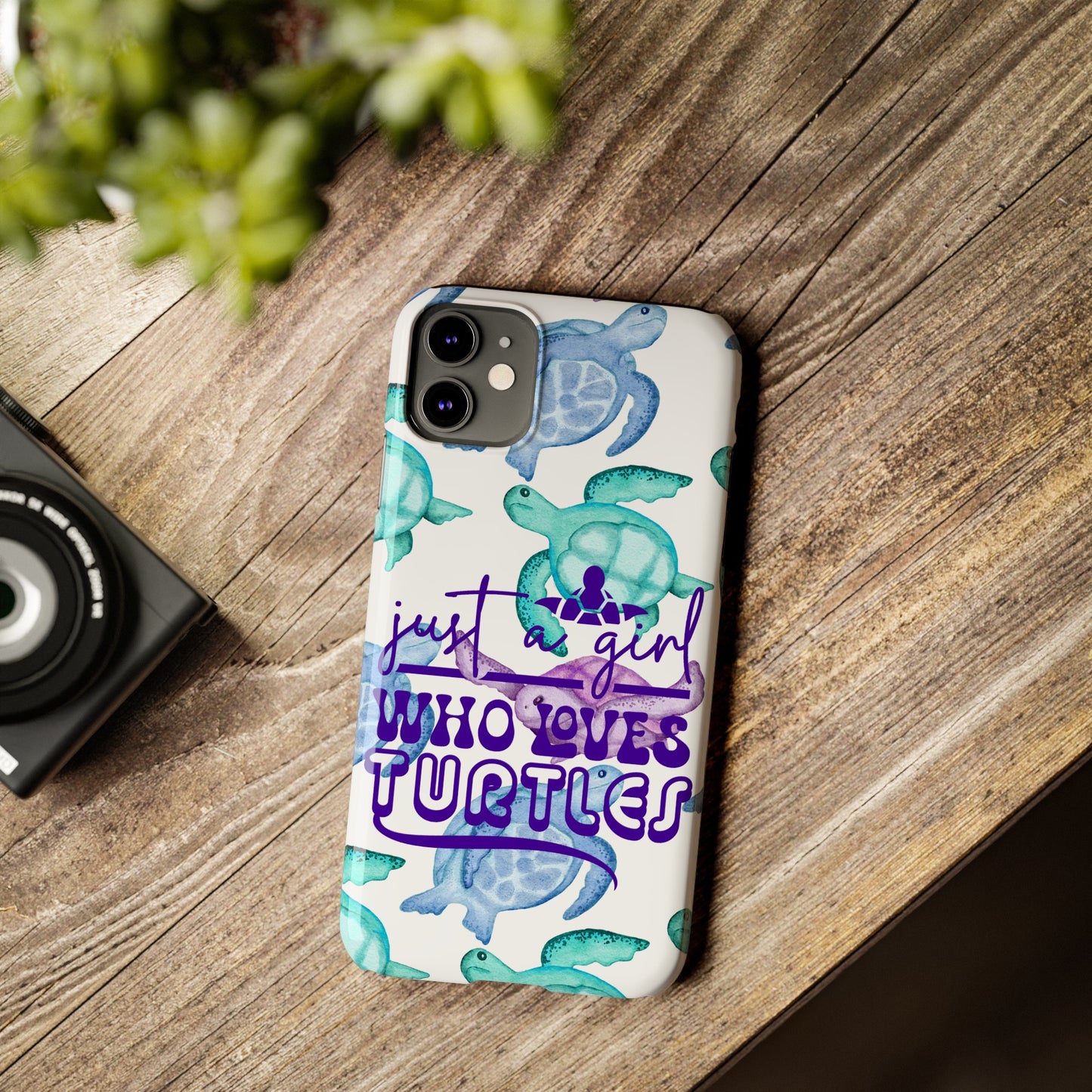 Iphone case with turquoise, blue and purple sea turtles that says  Just a Girl Who Loves Sea turtles laying on wood desk