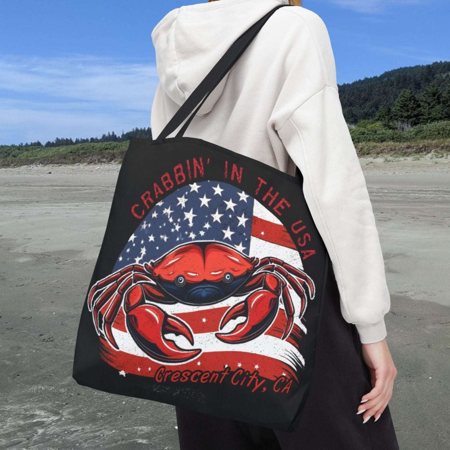 A black tote bag with an American Flag design with a crab coming out and says Crabbin' in the USA and Crescent City, CA.  