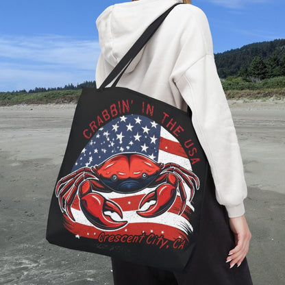A black tote bag with an American Flag design with a crab coming out and says Crabbin' in the USA and Crescent City, CA.  