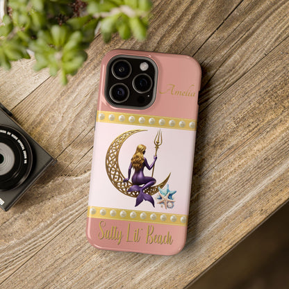 Phone case with a design of a mermaid and crescent moon on a pink background, placed on a wooden surface.