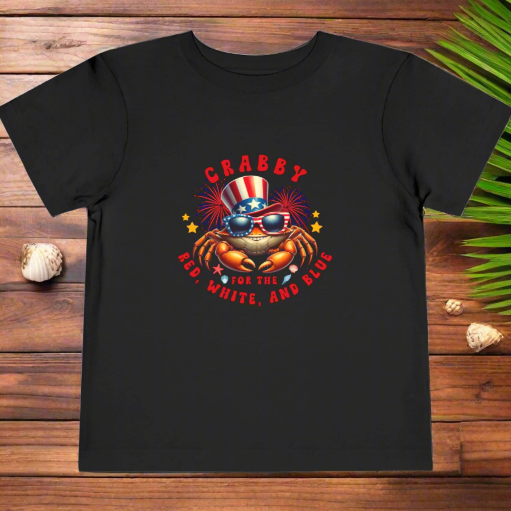 Black t-shirt with a colorful graphic of a crab wearing an American flag hat and sunglasses, with text 'CRABBY FOR THE RED, WHITE, AND BLUE' on a white background.