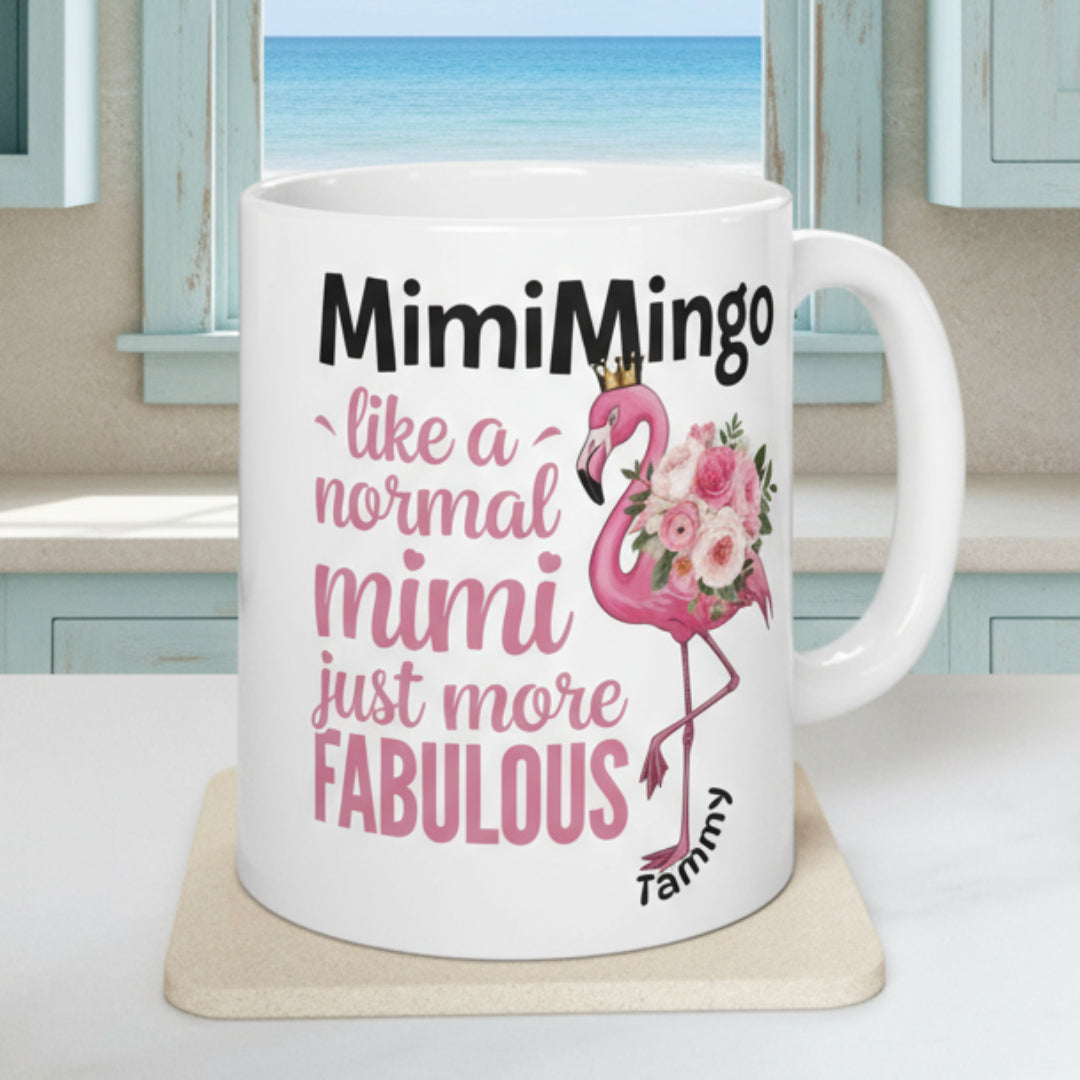 White mug with pink flamingo design and text on a white surface with plants and fruit in the background