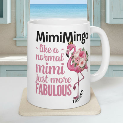 White mug with pink flamingo design and text on a white surface with plants and fruit in the background