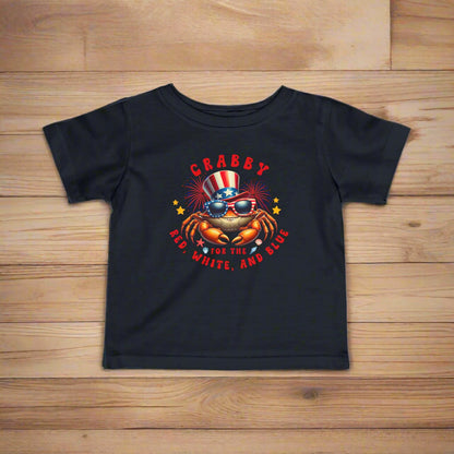 Black Infant t-shirt with a crab wearing an American flag top hat surrounded by fireworks and seashells with the phrase “Crabby for the Red, White, and Blue.”