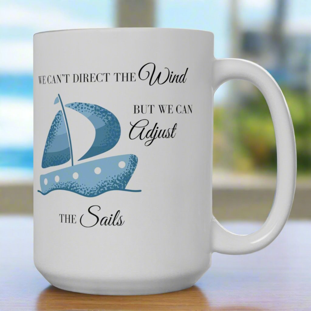 White mug with a blue sail boat that says We Can't Direct the Wind But We Can Adjust the Sails