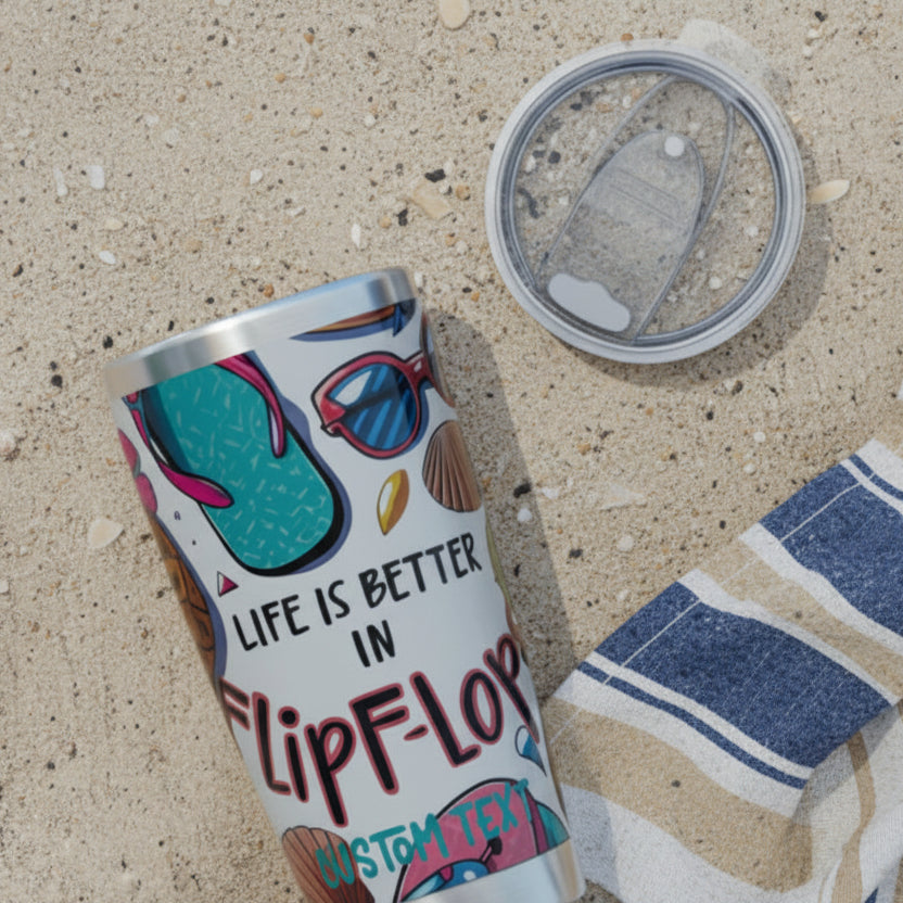 Tumbler with 'Life is Better in Flip-Flops' text and sunglasses design on the beach.