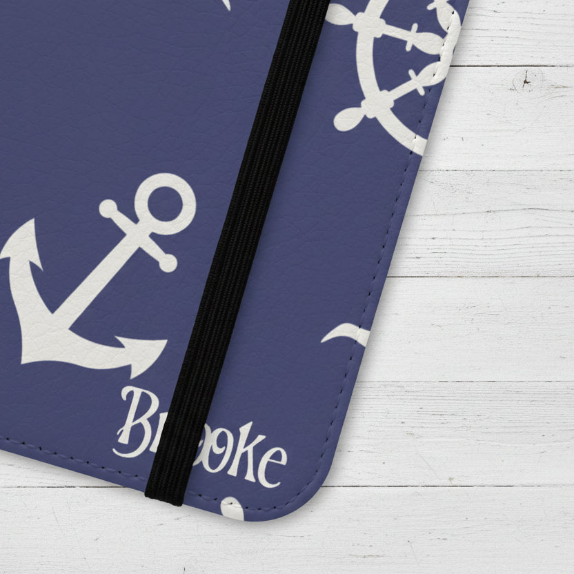 Nautical-themed flip phone case with anchor and ship wheel design on a blue background.