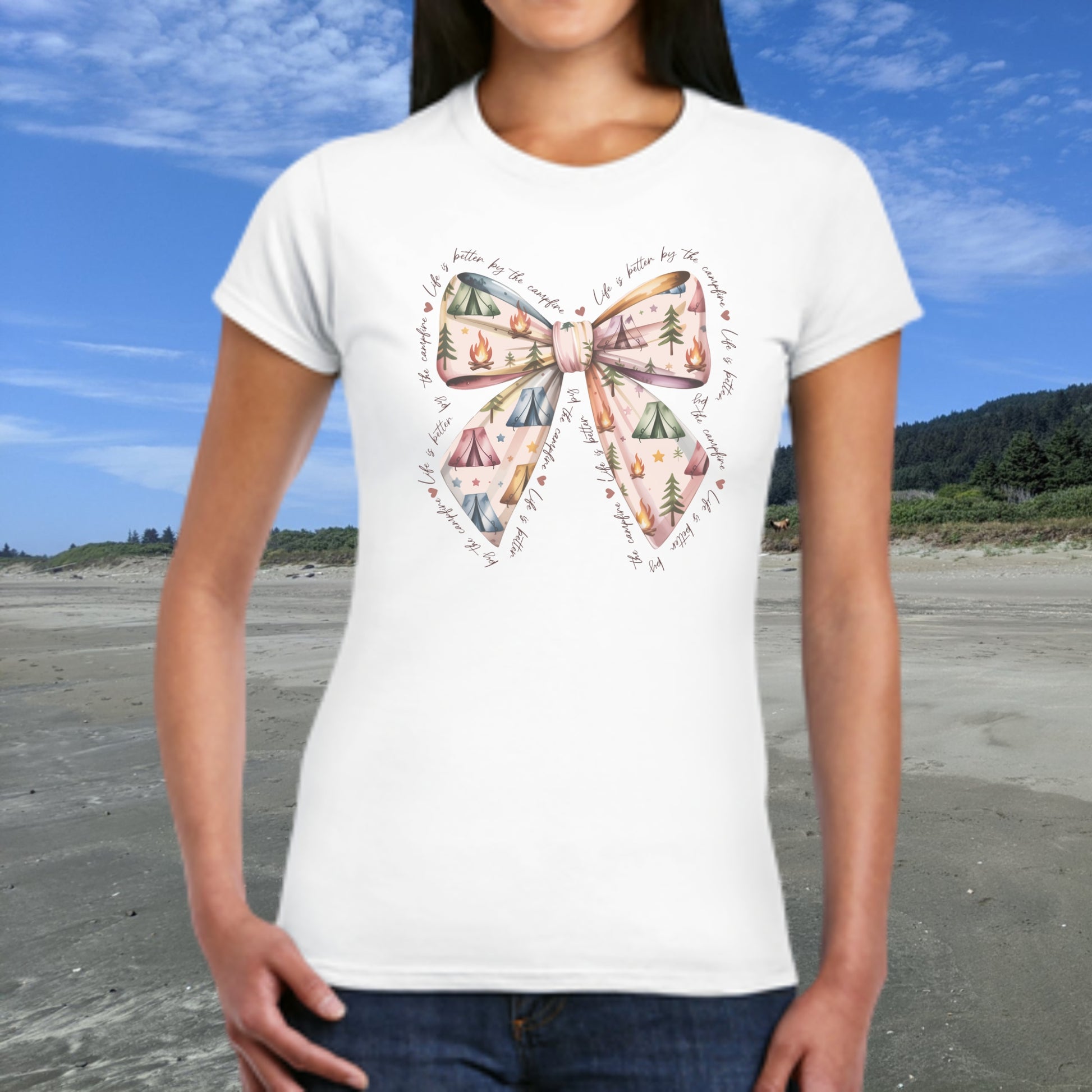 Person wearing a white t-shirt with a colorful bow design on a beach.