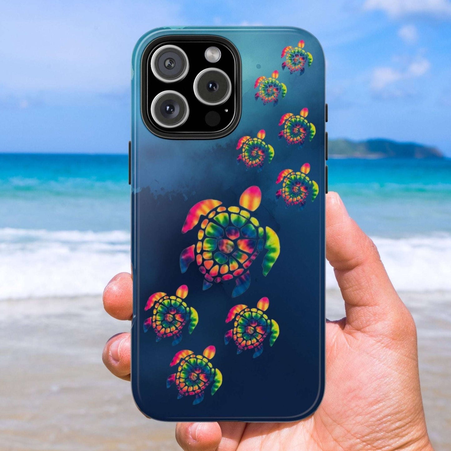 Phone case with colorful turtle design held by a hand on a beach