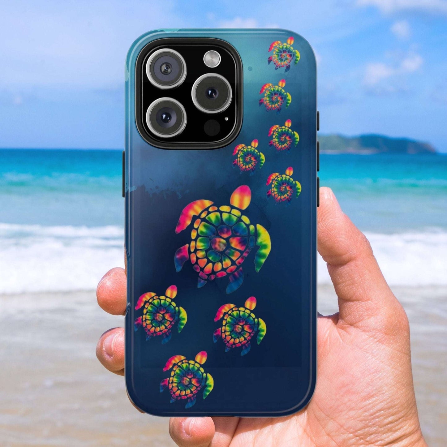 Phone case with colorful turtle design held by a hand on a beach