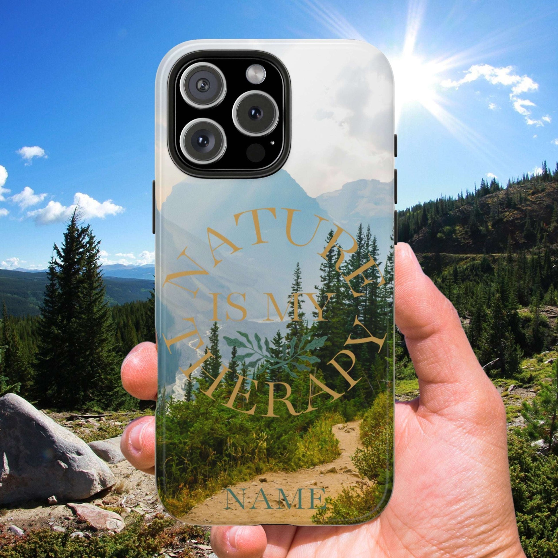 Phone case with nature design held in front of a scenic mountain landscape