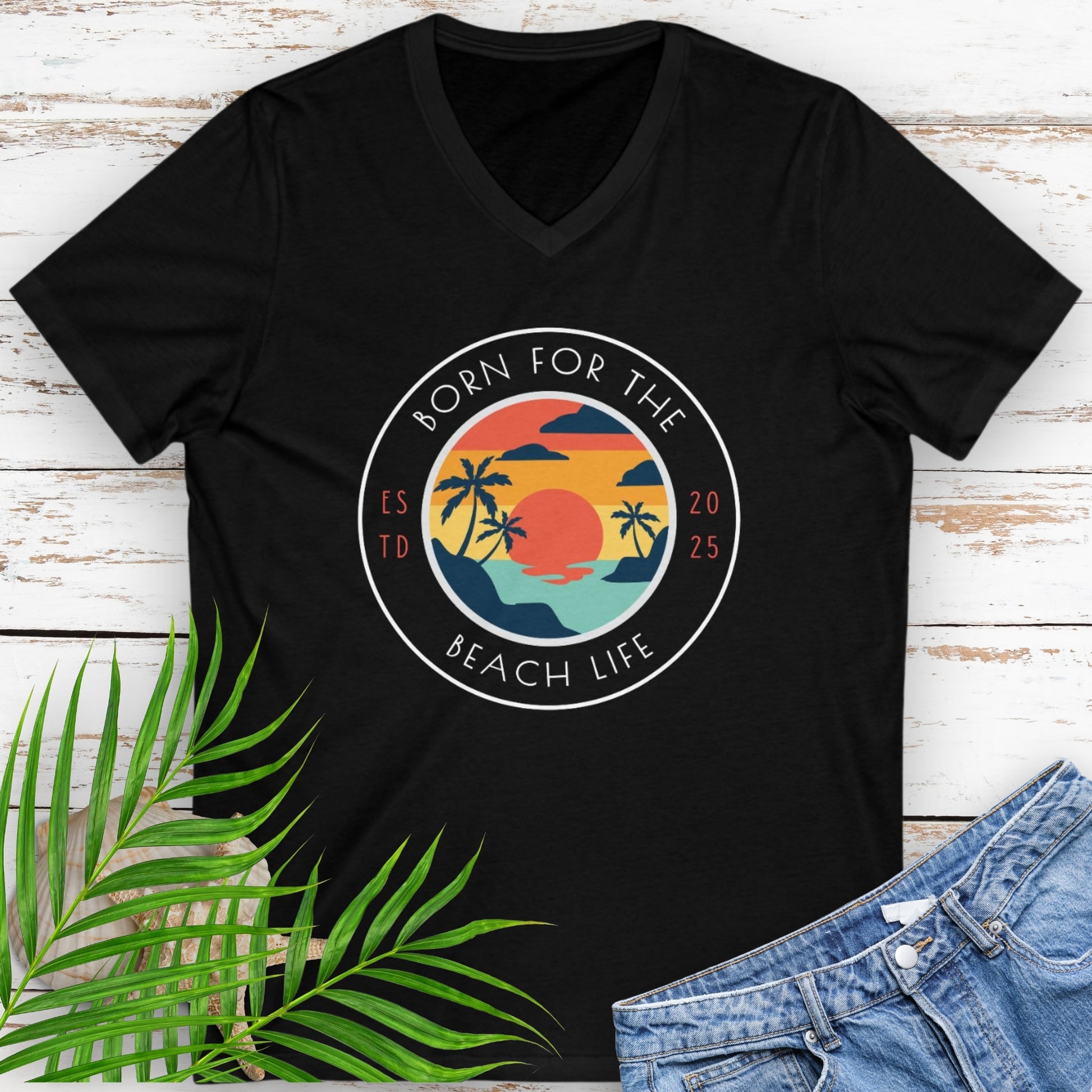Black v-neck t-shirt with circle design with a beach scene and the text “Born for the Beach Life.