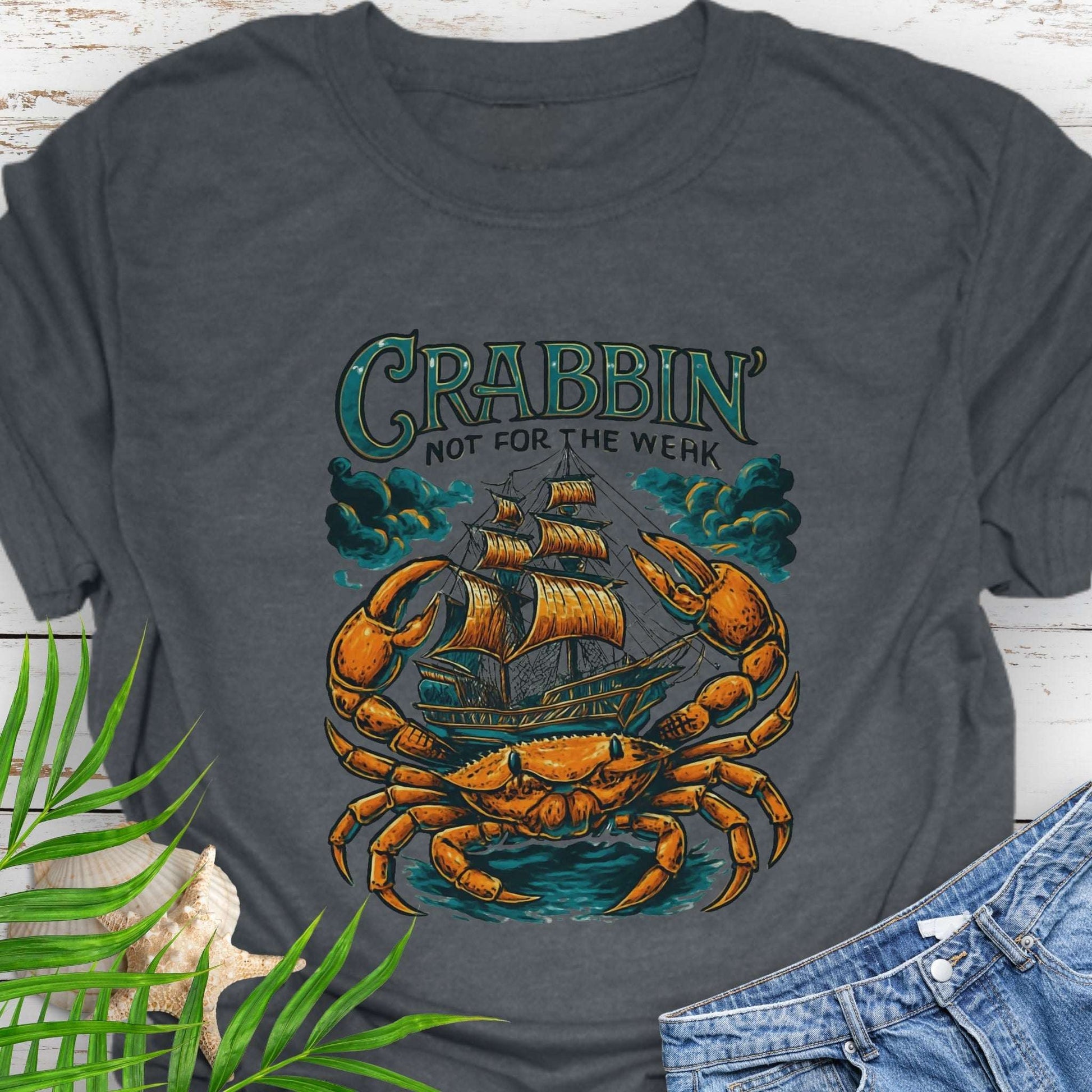 Gray t-shirt with a large crab enveloping a pirate ship with the text “Crabbin’s Not for the Weak” in an old-style font.