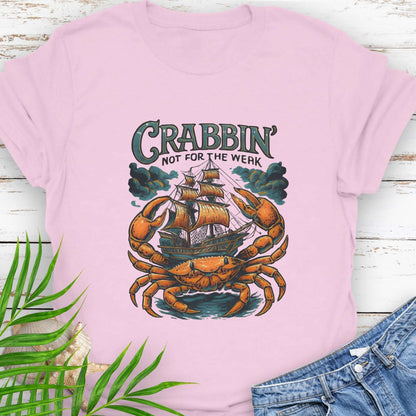 Pink t-shirt with a large crab enveloping a pirate ship with the text “Crabbin’s Not for the Weak” in an old-style font.