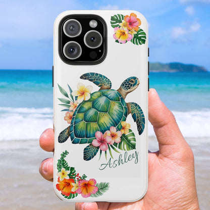Phone case with a turtle design and floral elements held against a beach background